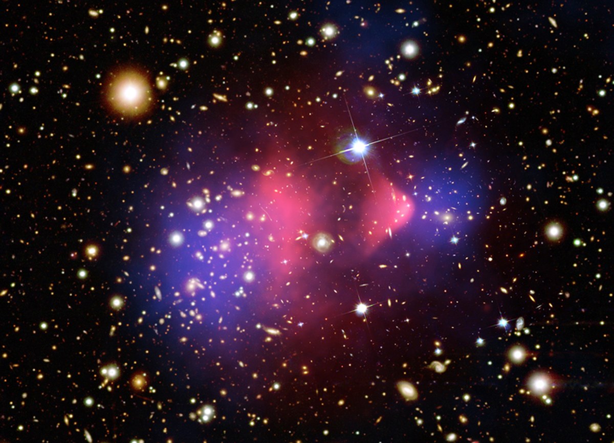 Two galaxy clusters after a collision, with the mass (blue) separated from the visible matter (pink). It is among the clearest evidence that dark matter exists, and among the least informative about what it actually is (Credit : X-ray NASA/CXC/CfA/M. Markevitch et al.; Optical NASA/STScI; Lensing map NASA/STScI, ESO WFI, Magellan/U.Arizona/D. Clowe et al.)