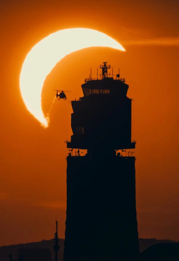 Helicopter, air control tower and a partial solar eclipse. Credit: Emmanuel Schawaller.