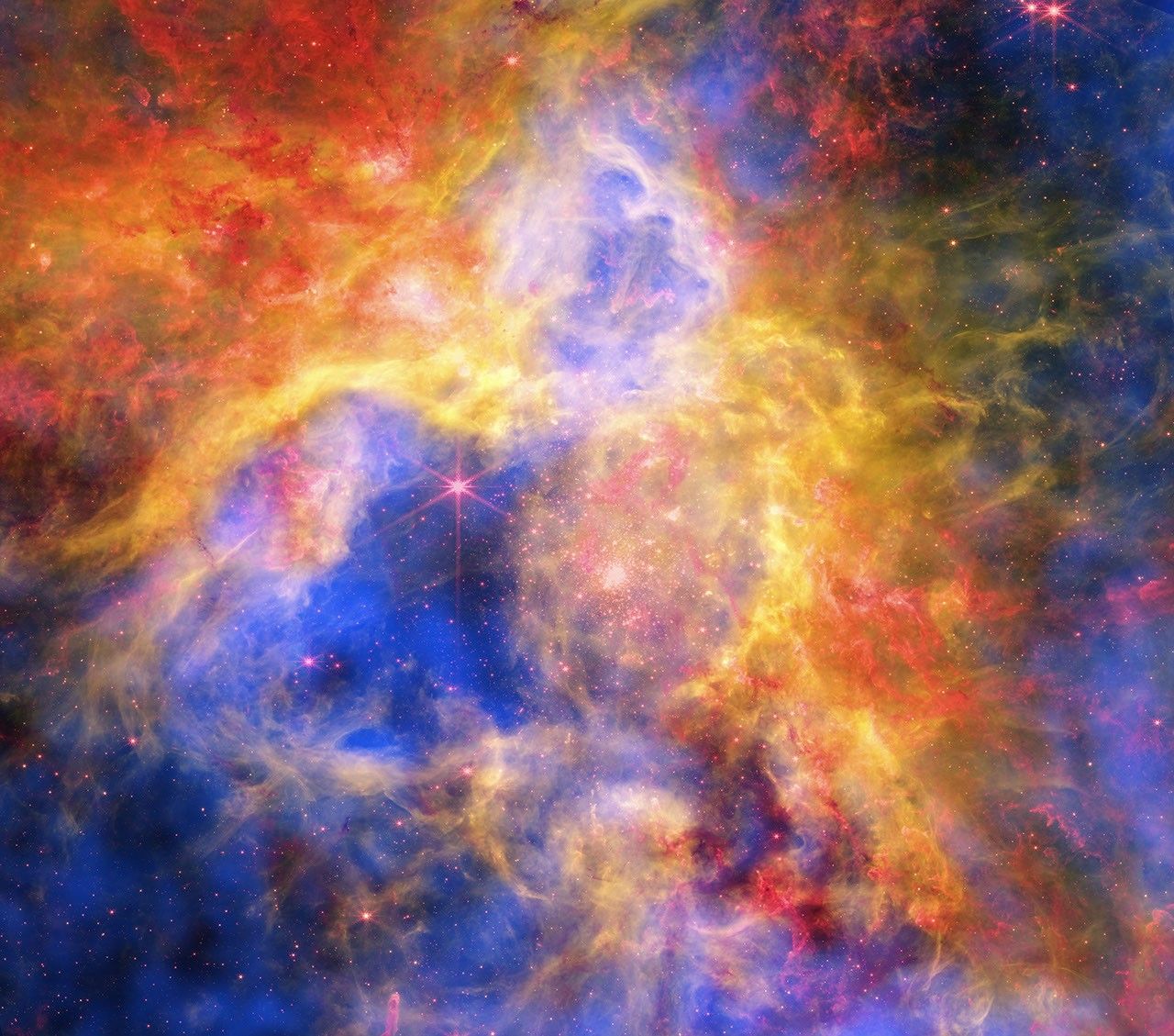 This multiwavelength image of the Tarantula Nebula, one of the brightest and largest regions of star formation to Earth, shows X-rays from Chandra that reveal gas that has been blown away in winds from the surfaces of young, massive stars and heated to millions of degrees by shock waves, like sonic booms from supersonic jets. The infrared data from Webb shows thousands of young stars, plus swaths of cool dust that will provide the ingredients to one day form new stars and planets. Hubble optical data uncovers hydrogen gas that is warmer than seen with Webb, as well as some individual stars through the nebula.