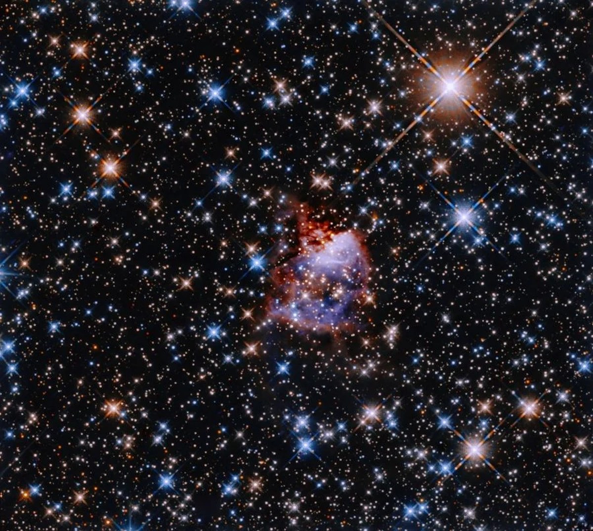 This Hubble image shows the star formation region G033.91+0.11. A central nebula lies in the center of a glittering backdrop of multicoloured stars. The nebula is reflecting light from a bright and massive young protostar. Scientists use the initial mass function to estimate the mass ratios of stars created in such starbirth regions. Image Credit: NASA, ESA, and R. Fedriani (Instituto de Astrofisica de Andalucia); Processing: Gladys Kober (NASA/Catholic University of America)