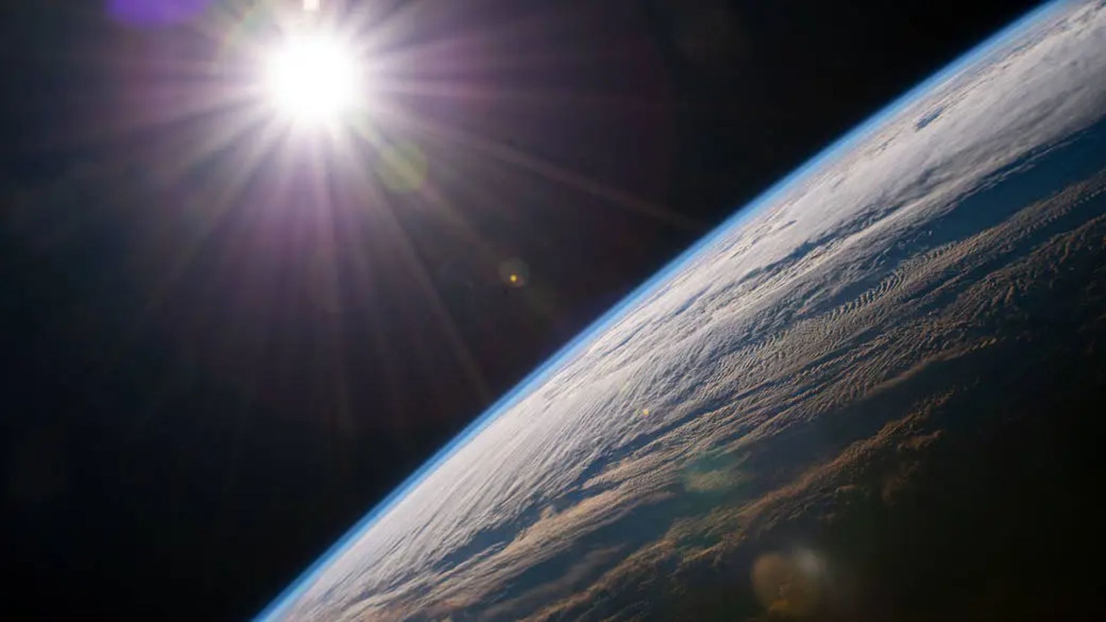 An image of the earth with the sun shining in the top left.