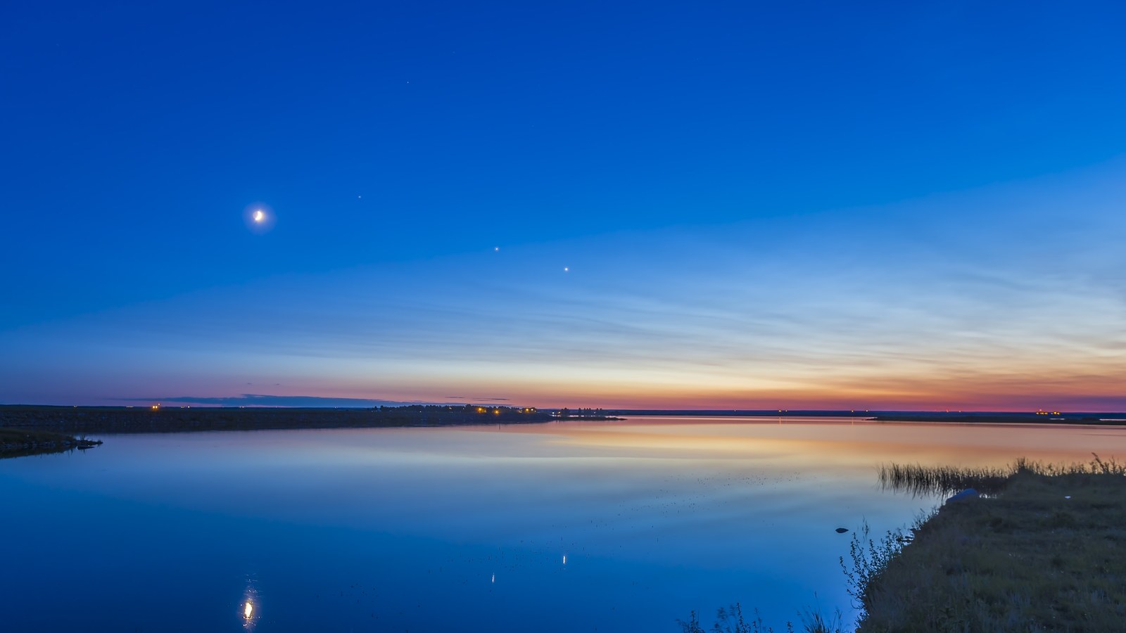 night sky at twlight with moon to the left and two bright points of light in the center of the sky, venus is on the right and jupiter the left