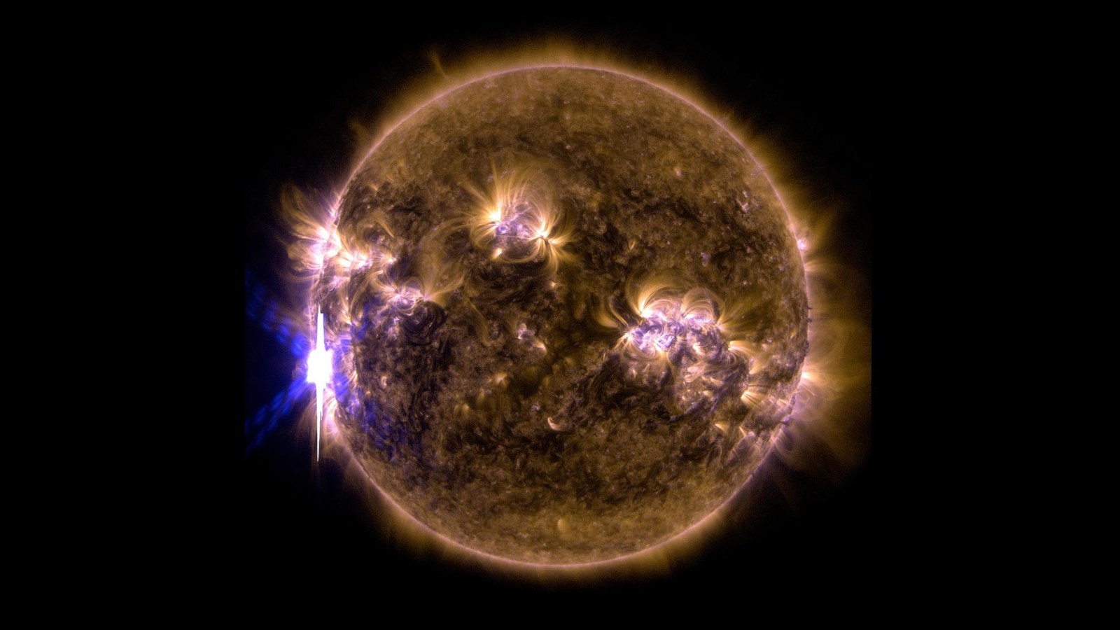 A filtered sun that's yellow and purple. A solar flare is visible to the left.