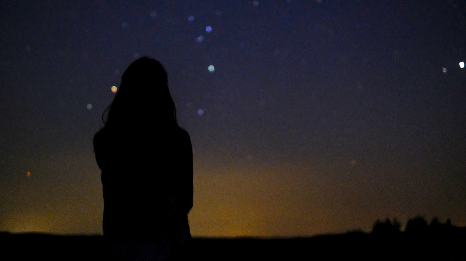 a woman looks at a sky full of stars