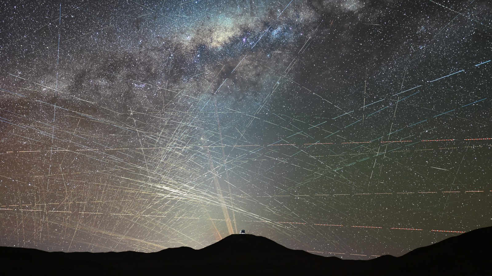 bright streaks of light crisscross through a night sky