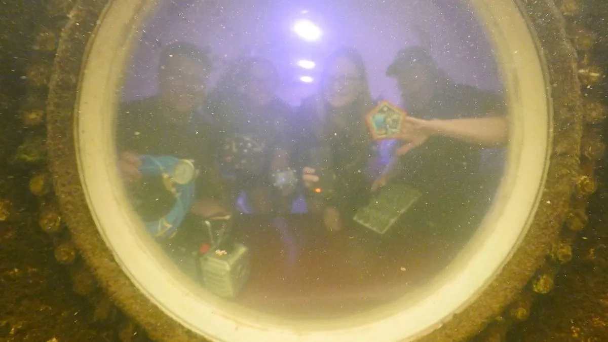 photo of three women and one man, seen fuzzily through a circular porthole