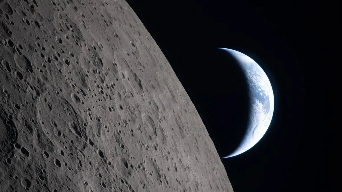 photo from a spacecraft flying around the moon, showing a crescent earth beyond the lunar limb
