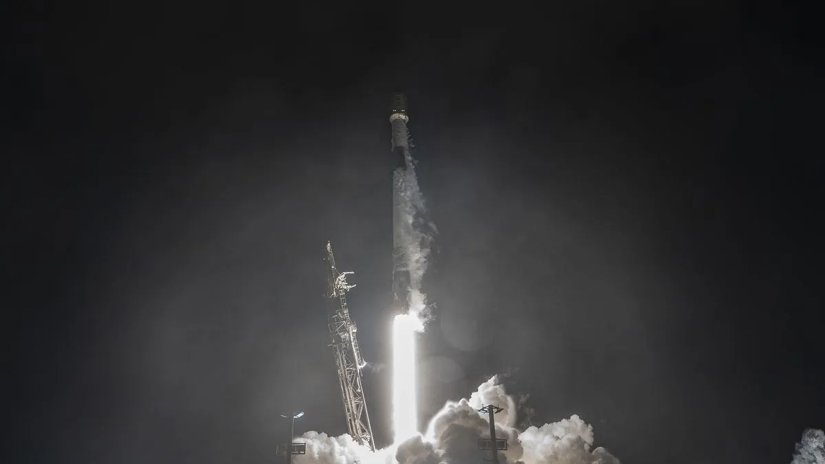 A white rocket blasts off in the dark of night.