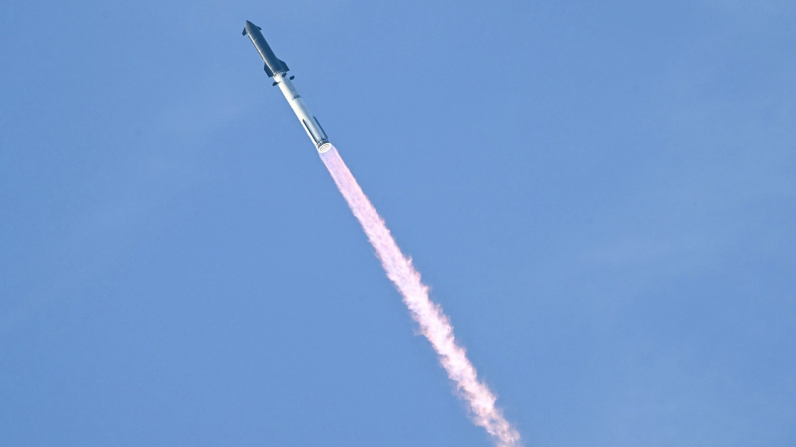 a rocket launches against a light blue sky.
