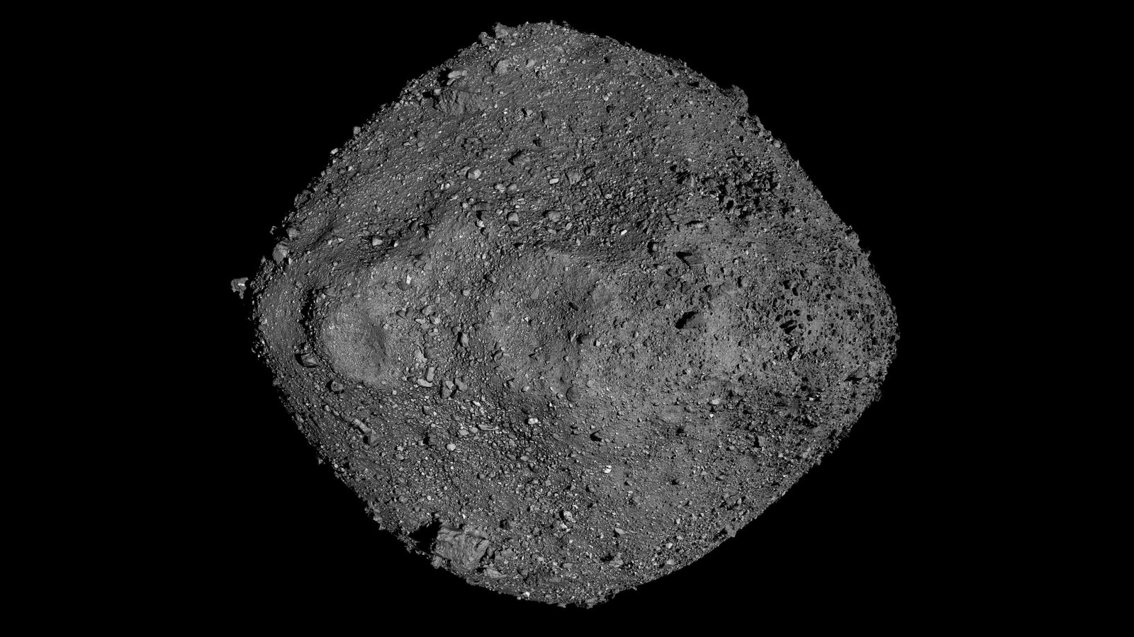 A gray rock with small pebbles on it against a dark background.