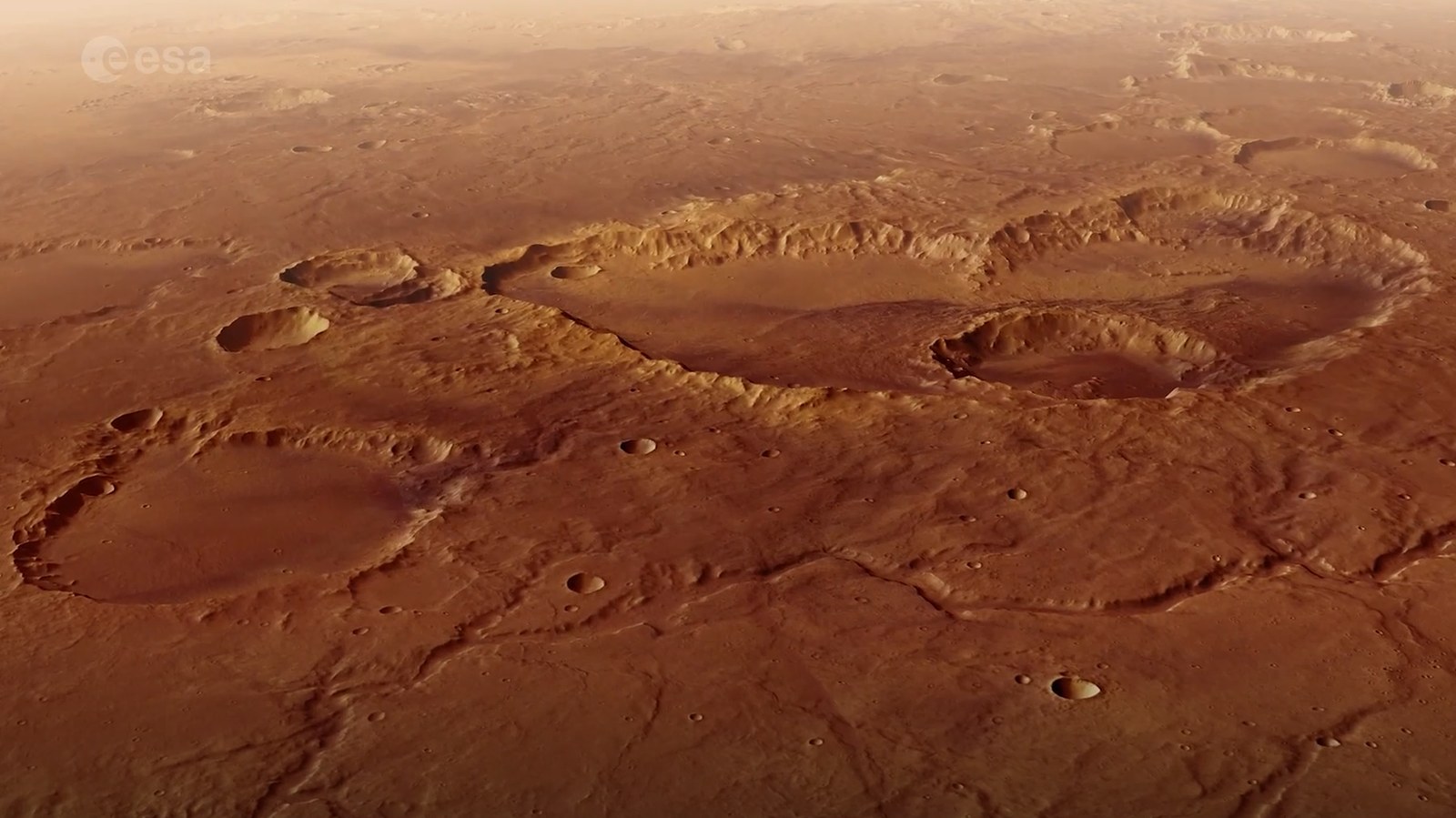 a rusty red landscape shows a smattering of craters from a high altitude.