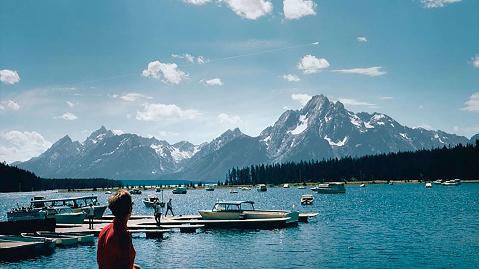a meteorite is seen falling to Earth during a bright sunny day over a mountain range and lake.