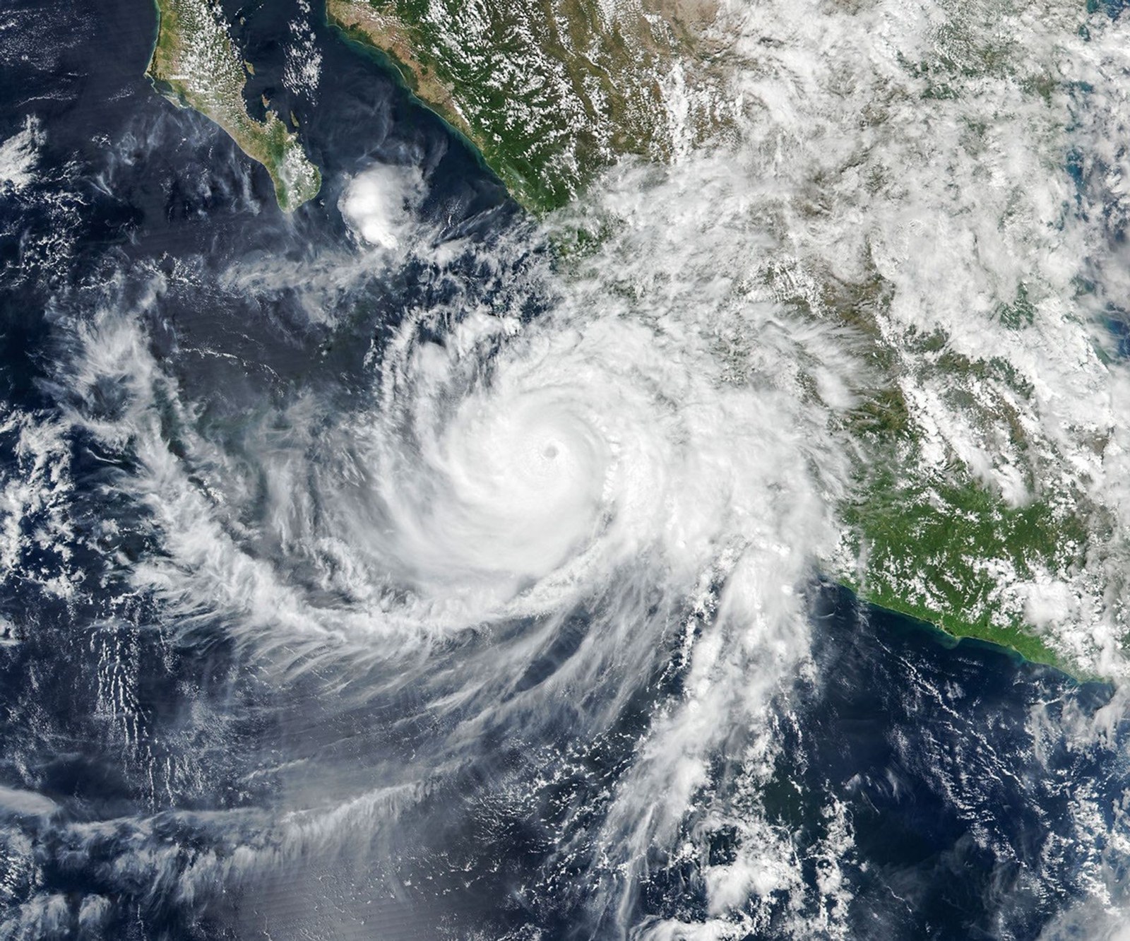 The well-defined eye of Hurricane Simon lies just off Mexico’s Pacific coast. Some outer cloud bands of the spiraling storm extend over land.